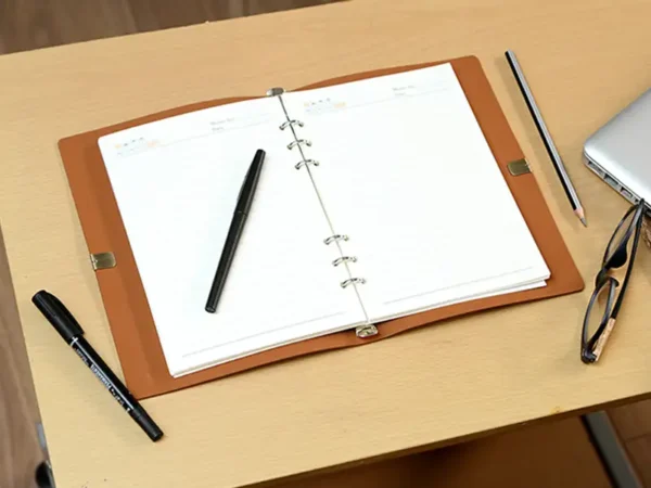 Libreta Corvino tipo carpeta en poliuretano con cierre de resorte y detalle metálico para laboratorios farmacéuticos. Libreta abierta