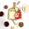 Set Para Quesos Mezzo en madera de acacia con utensilios de acero inoxidable para sector gastronómico y gourmet. Foto con la tabla y quesos y frutas.