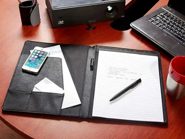 Carpeta Harbel de curpiel negro con block A4 y compartimentos organizadores para oficina y eventos. Carpeta sobre escritorio