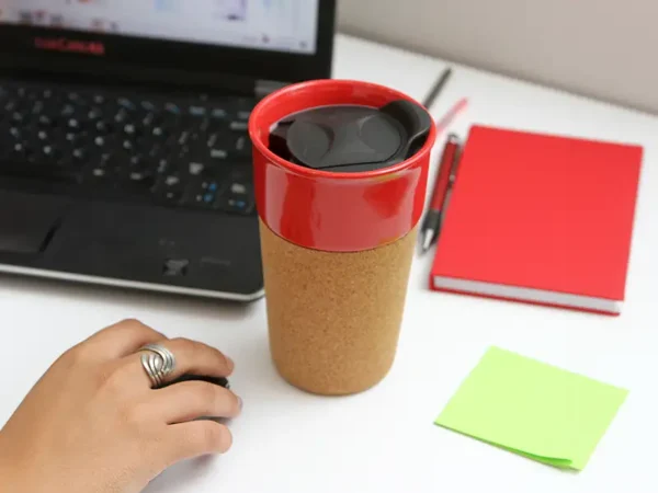 Vaso Tofanello de cerámica de 400 ml con base de corcho natural y tapa abre fácil en color rojo sobre un escritorio.