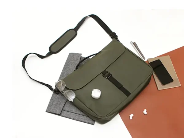Porta Laptop Allaire de curpiel con compartimento para laptop hasta 18”, correa ajustable con cojín y broche metálico, en colores azul, beige, negro y verde militar Fotografía de acercamiento a colores disponibles.
