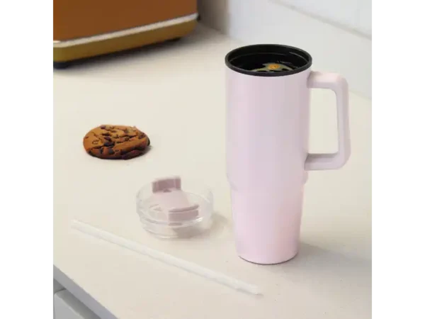 Mug Mega de 880ml con popote y acabado mate en colores rosa para transporte y turismo. Sobre una mesa