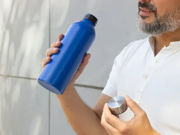 Botella de aluminio Tulum acabado mate colores negro blanco y azul con tapa de acero inoxidable para merchandising automotriz de Dot Factory. Muestra de uso.