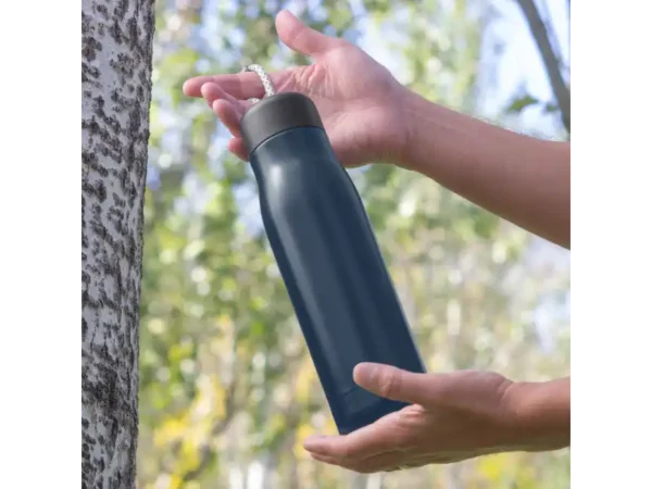 Botella térmica Montana, de acero inoxidable doble pared con correa gris para viajes y auto. Foto en el bosque