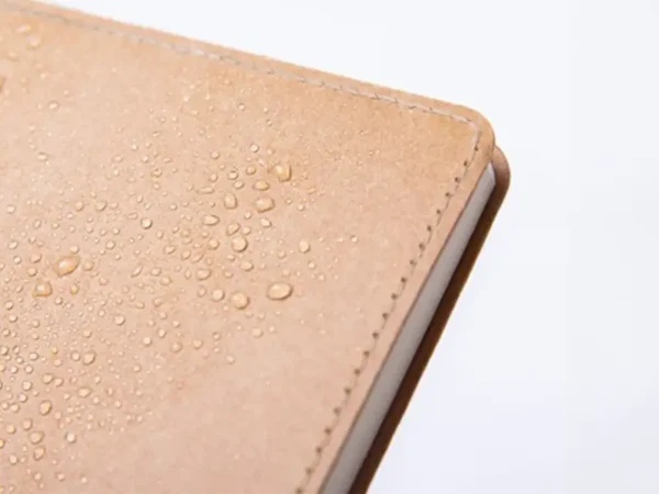 Libreta ecológica Tallin de papel kraft lavable disponible en color café, azul y negro para branding corporativo de Dot Factory. Detalle, contra agua.