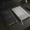 Libreta GAM con tapa bicolor de poliuretano suave al tacto, hojas crema rayadas y cierre de banda elástica.