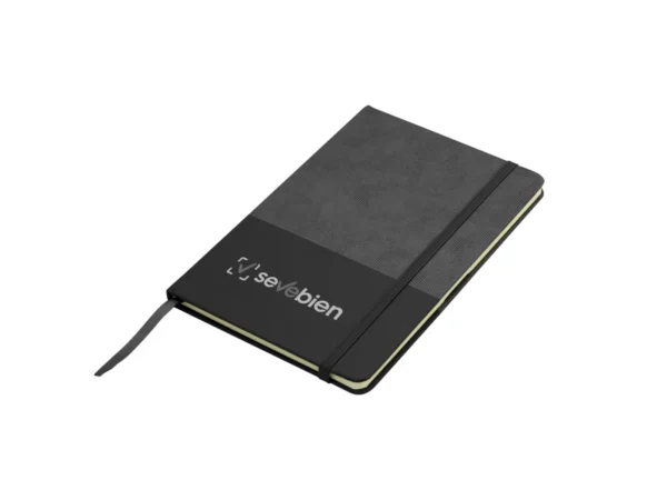 Libreta GAM con tapa bicolor de poliuretano suave al tacto, hojas crema rayadas y cierre de banda elástica.