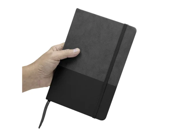 Libreta GAM con tapa bicolor de poliuretano suave al tacto, hojas crema rayadas y cierre de banda elástica.
