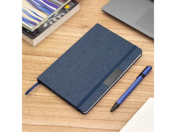 Libreta GRETA sustentable fabricada en RPET con placa metálica para grabado láser y cierre elástico.