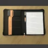 Porta Documentos Yakarta con cierre en zipper, incluye block de notas, portabolígrafos y detalle de lengüeta en curpiel.