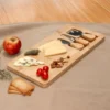 Tabla de quesos CHEDDAR. Tabla de bambú con cuchillo, tenedor y espátula de acero inoxidable sobre superficie clara